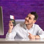 front-view-office-worker-sitting-his-working-place-holding-tickets-passport_179666-25579